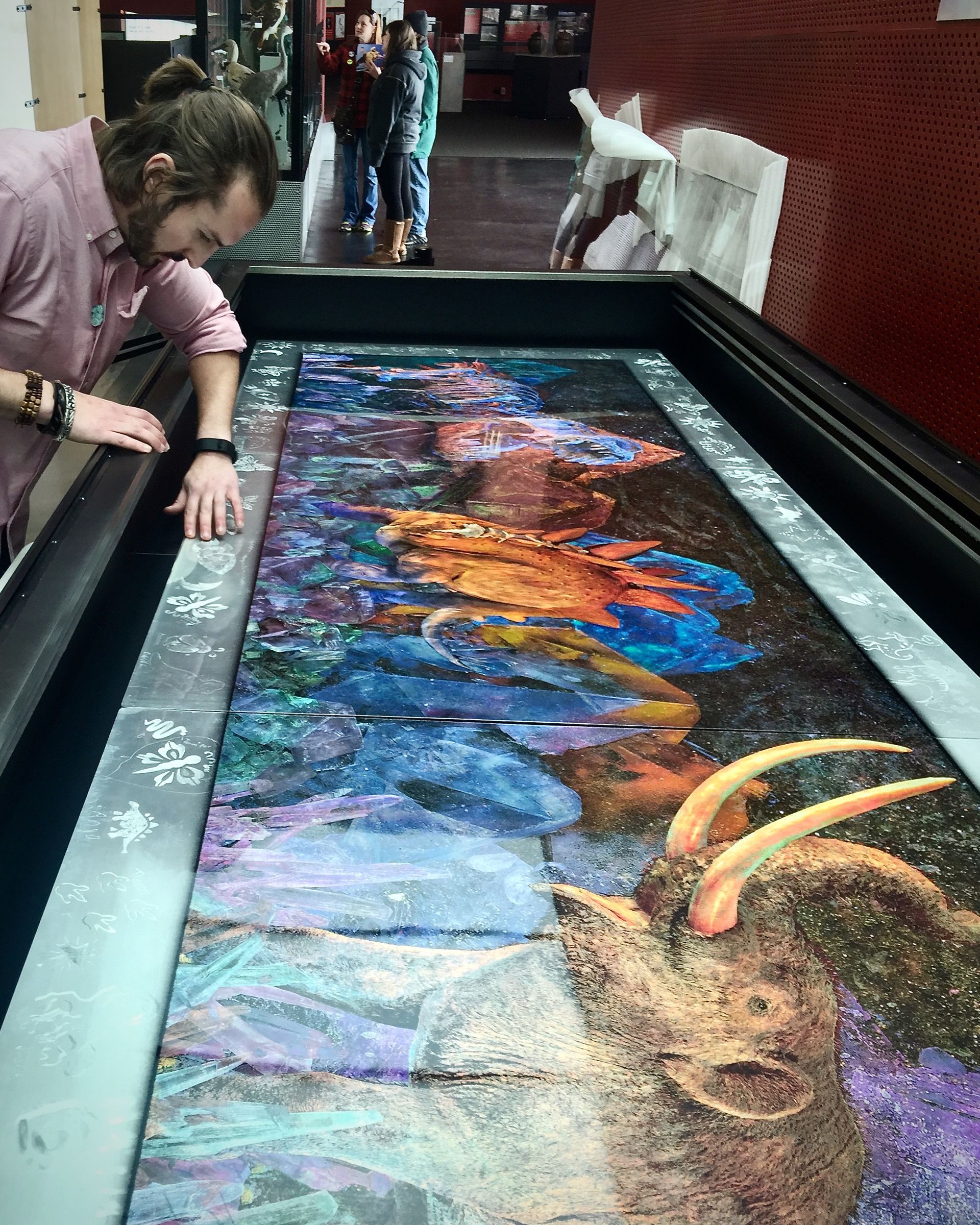 A man is touching a painting of a deer on a table.