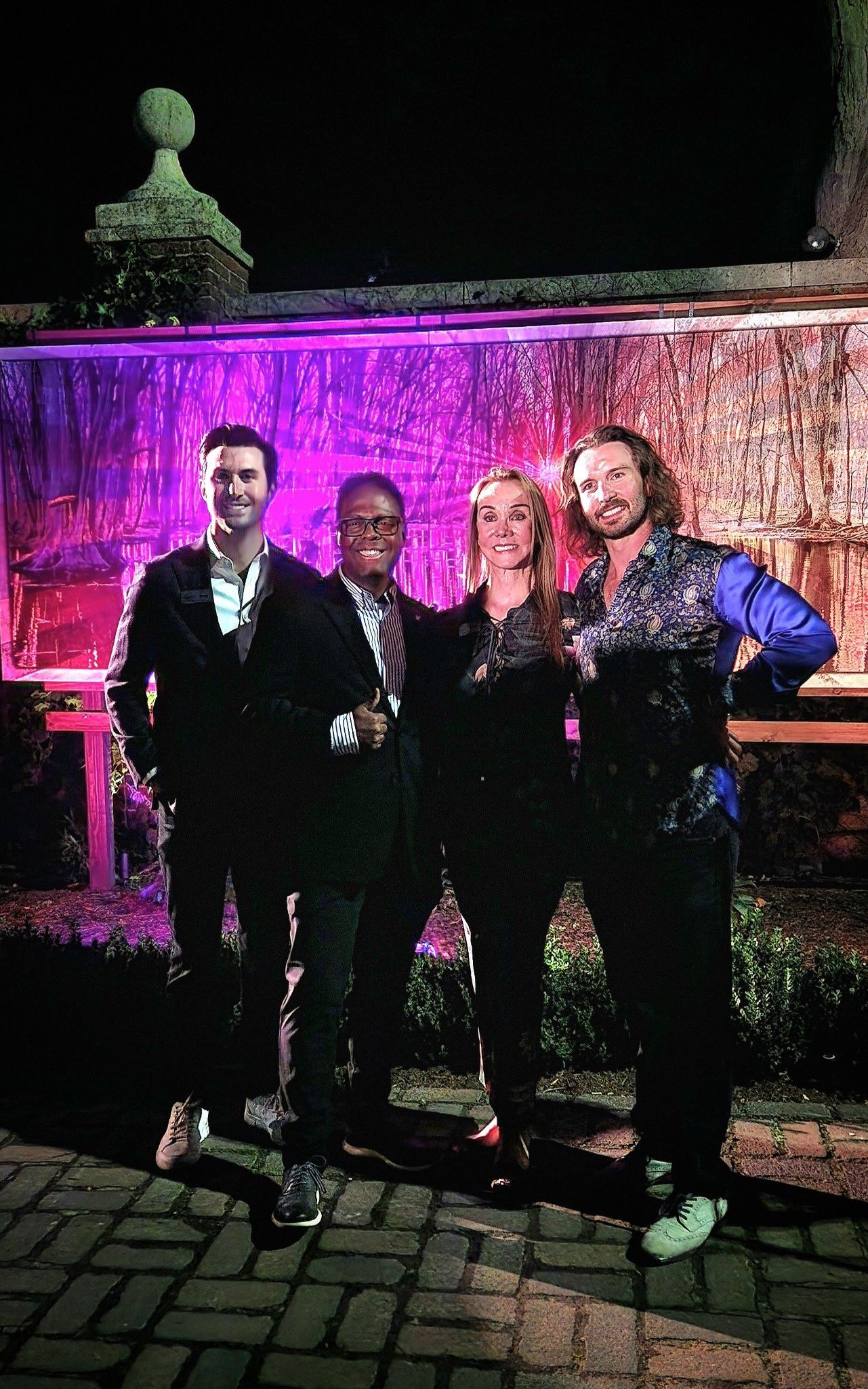 A group of people standing next to each other in front of a fountain at night.