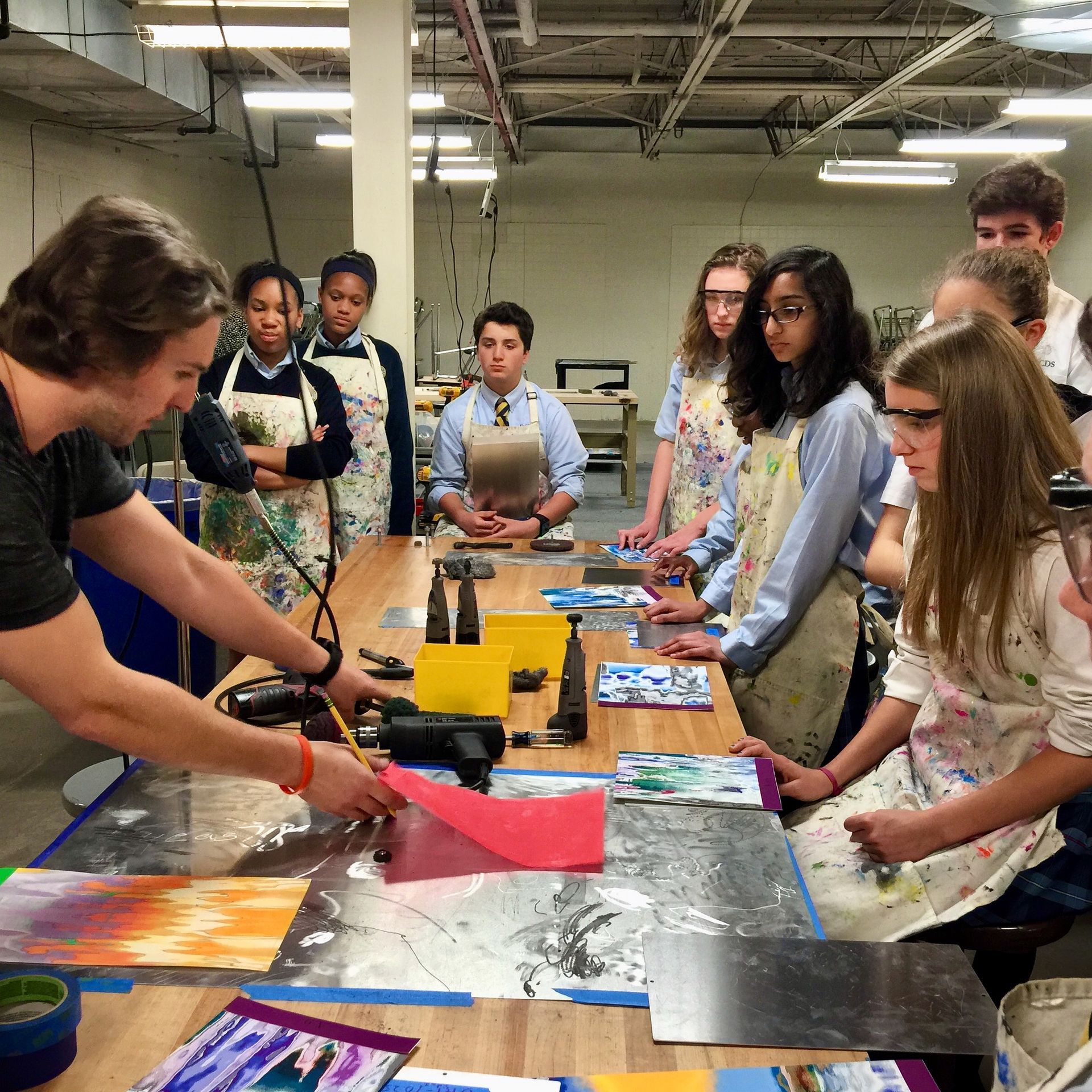 A group of people are sitting around a table in an art class