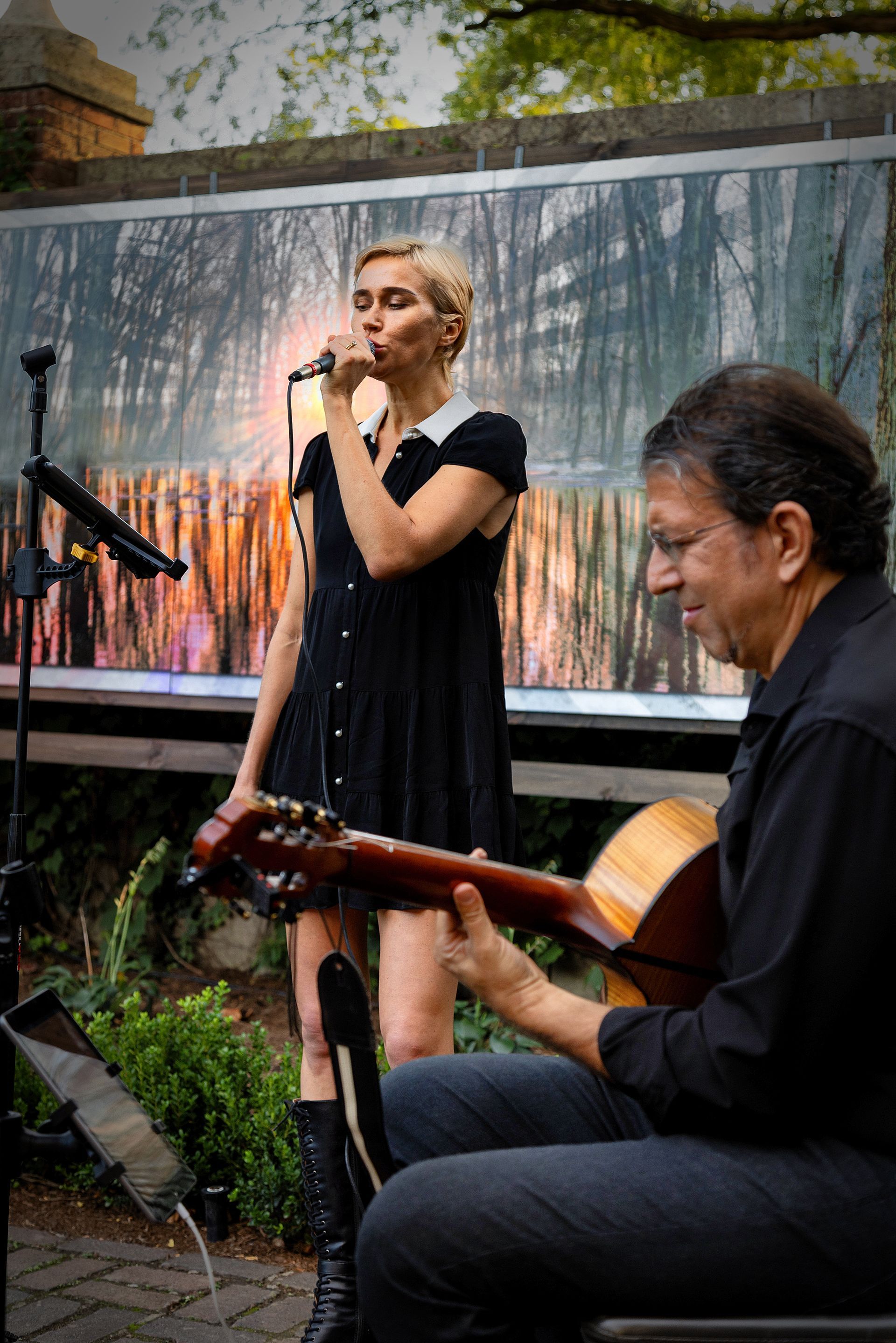 A woman is singing into a microphone while a man plays a guitar.