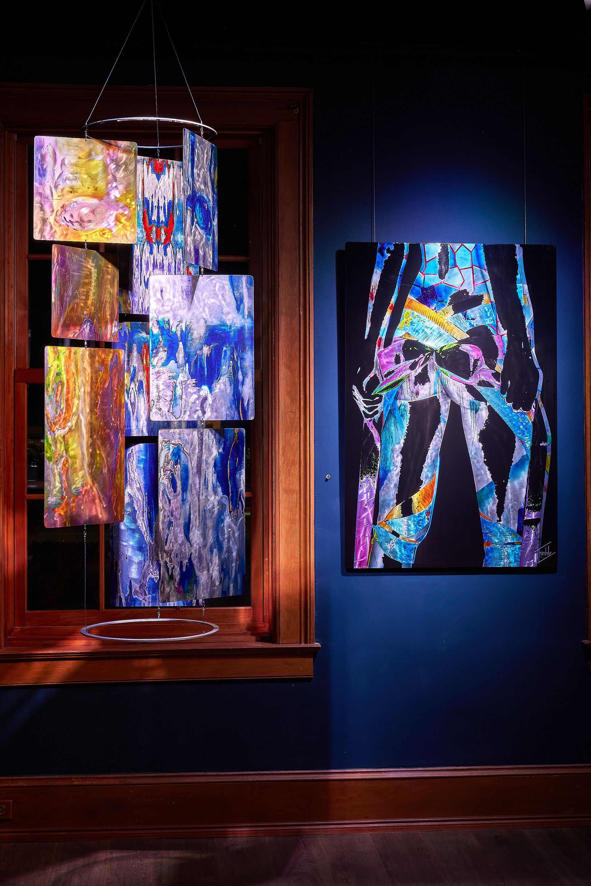 A painting is hanging on a wall next to a window.