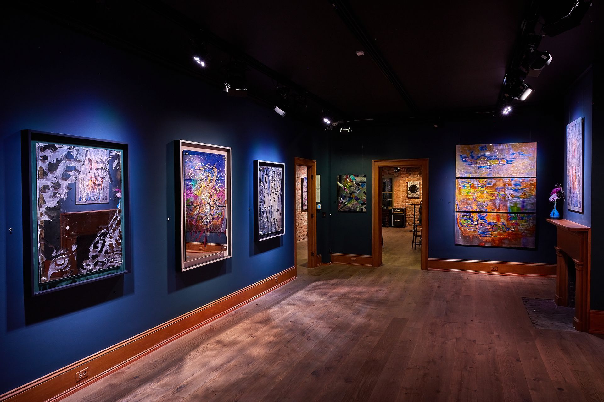 A room with a lot of paintings on the wall and a wooden floor.