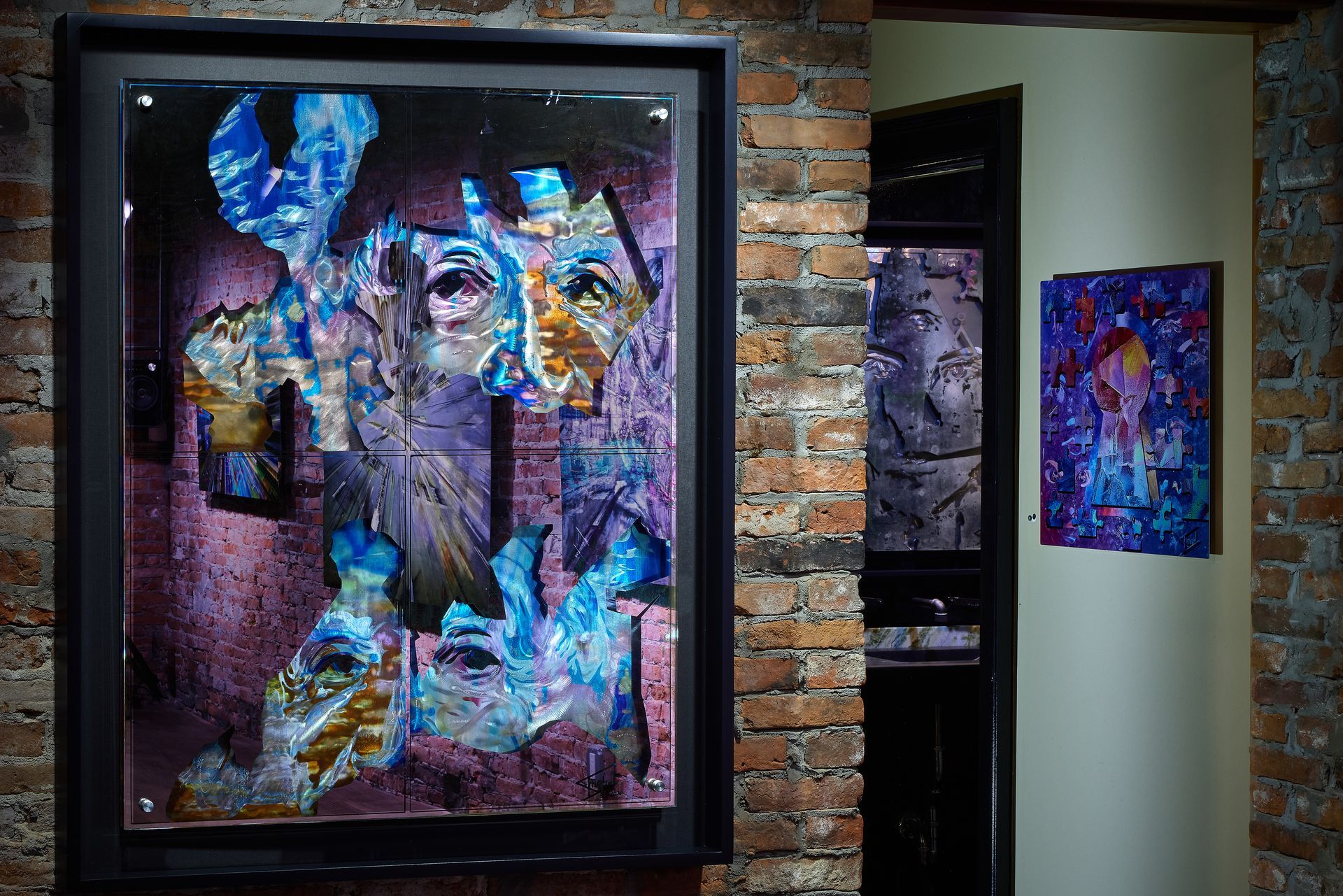 A painting is hanging on a brick wall next to another painting.