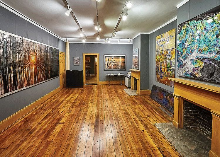 A large room with wooden floors and arts on the wall.