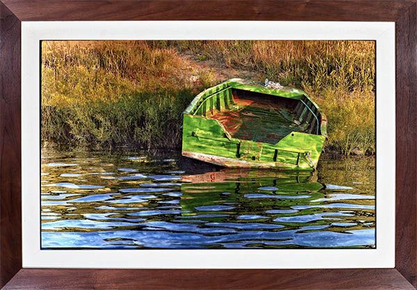 A green boat is floating on top of a body of water.