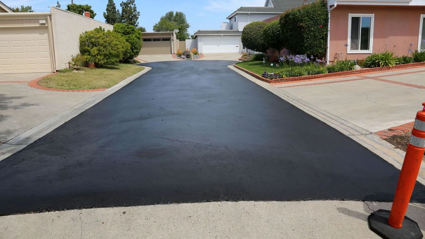 A newly paved driveway in a residential neighborhood next to a house.