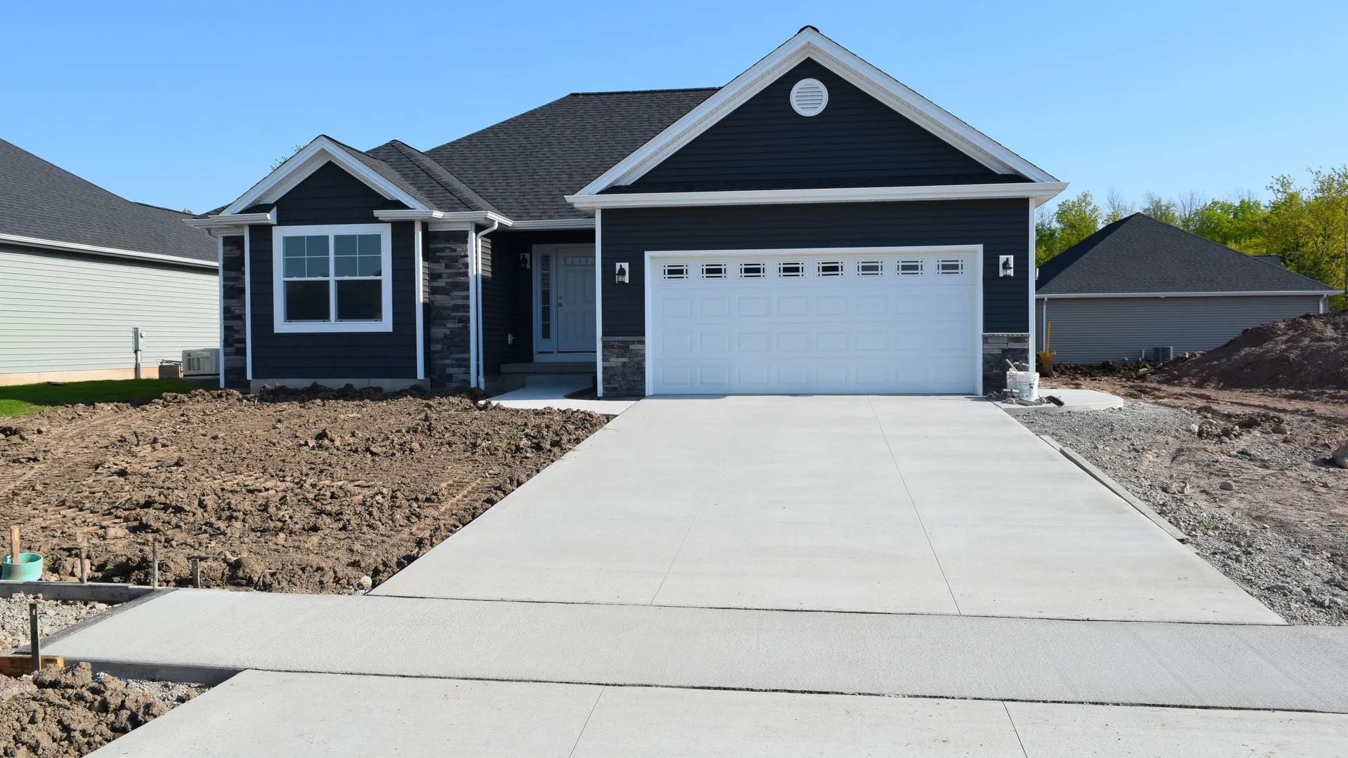 A black house with a white garage door and a concrete driveway