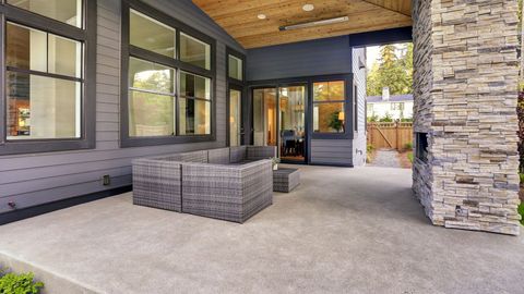 A patio with a couch and a fireplace in front of a house.