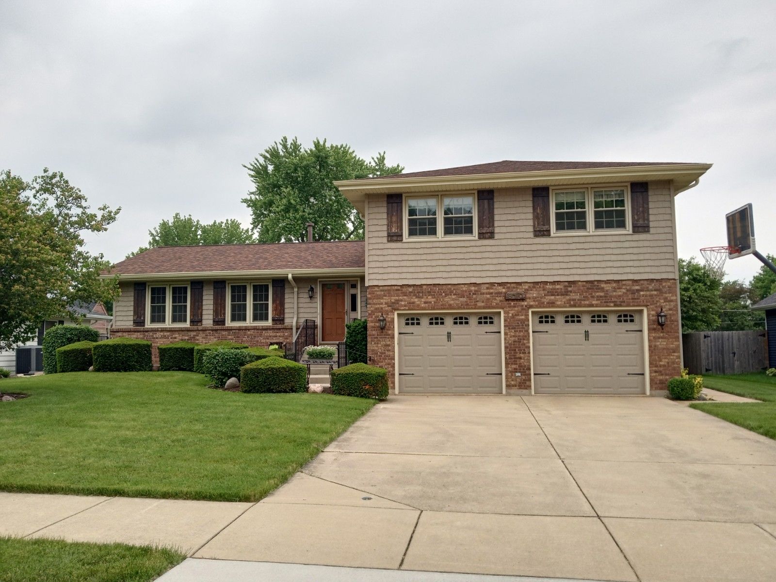A house with two garage doors and a basketball hoop in front of it