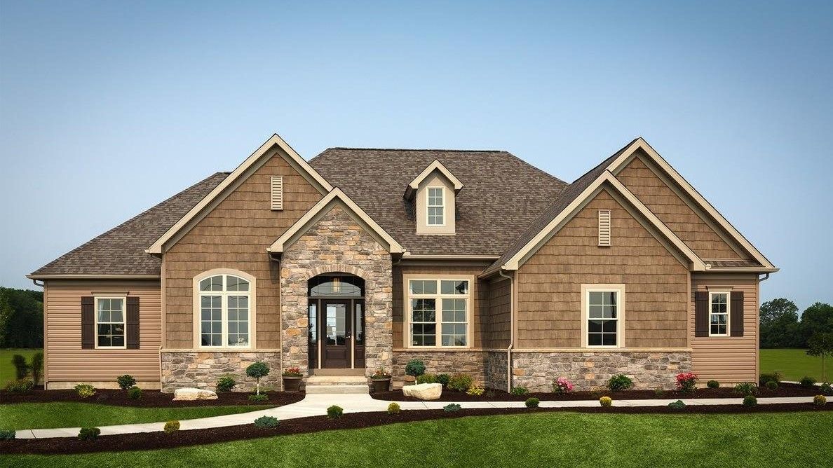 A large brown house with a stone facade is sitting on top of a lush green field