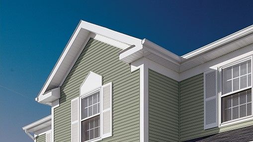 A house with green siding and white shutters against a blue sky