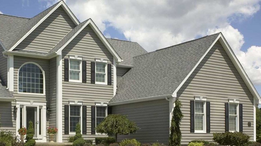 A large house with a gray roof and black shutters