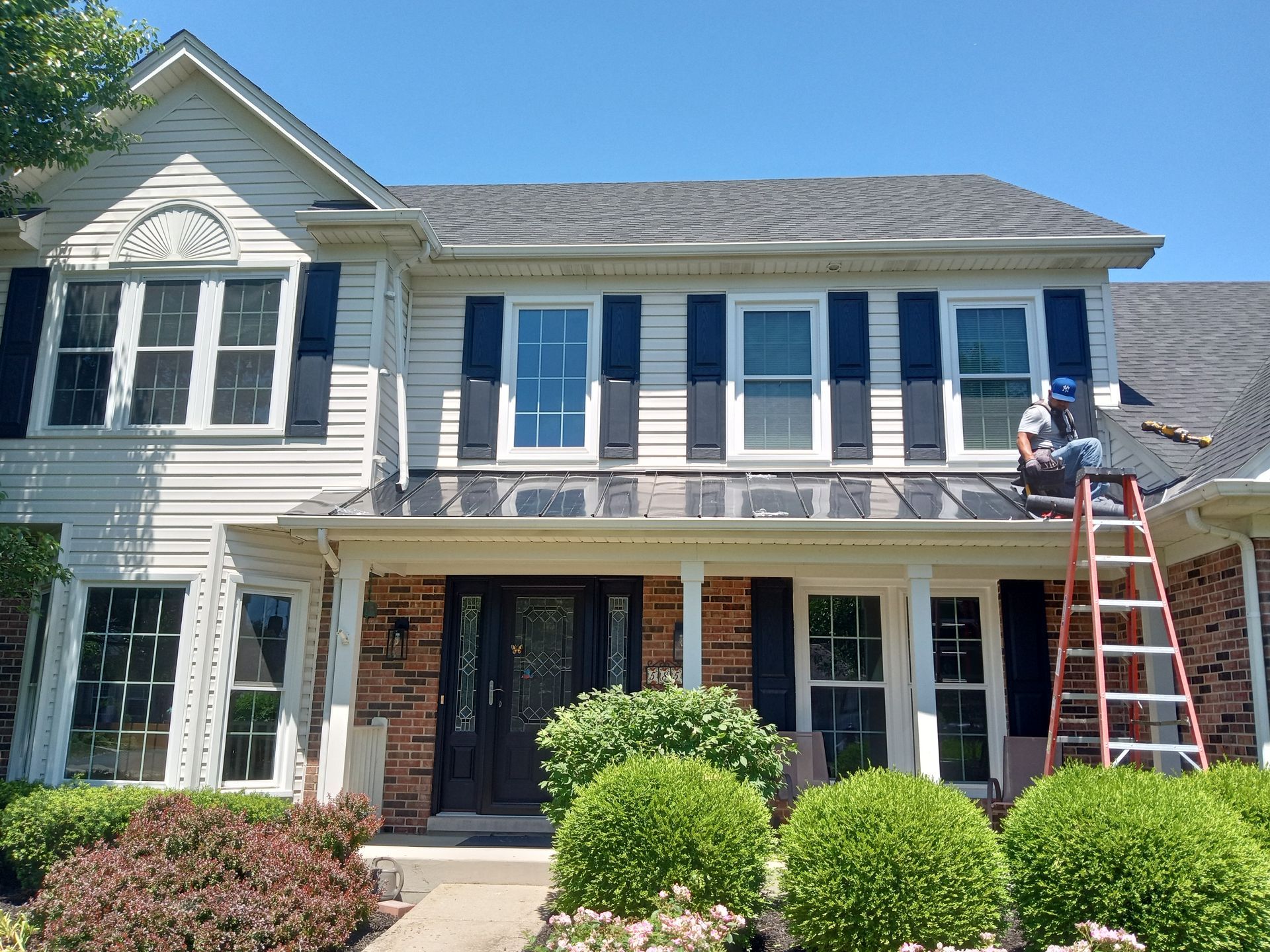 A man is sitting on a ladder in front of a house