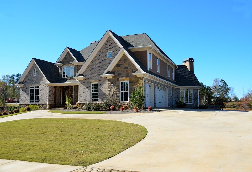 A large brick house with a concrete driveway in front of it