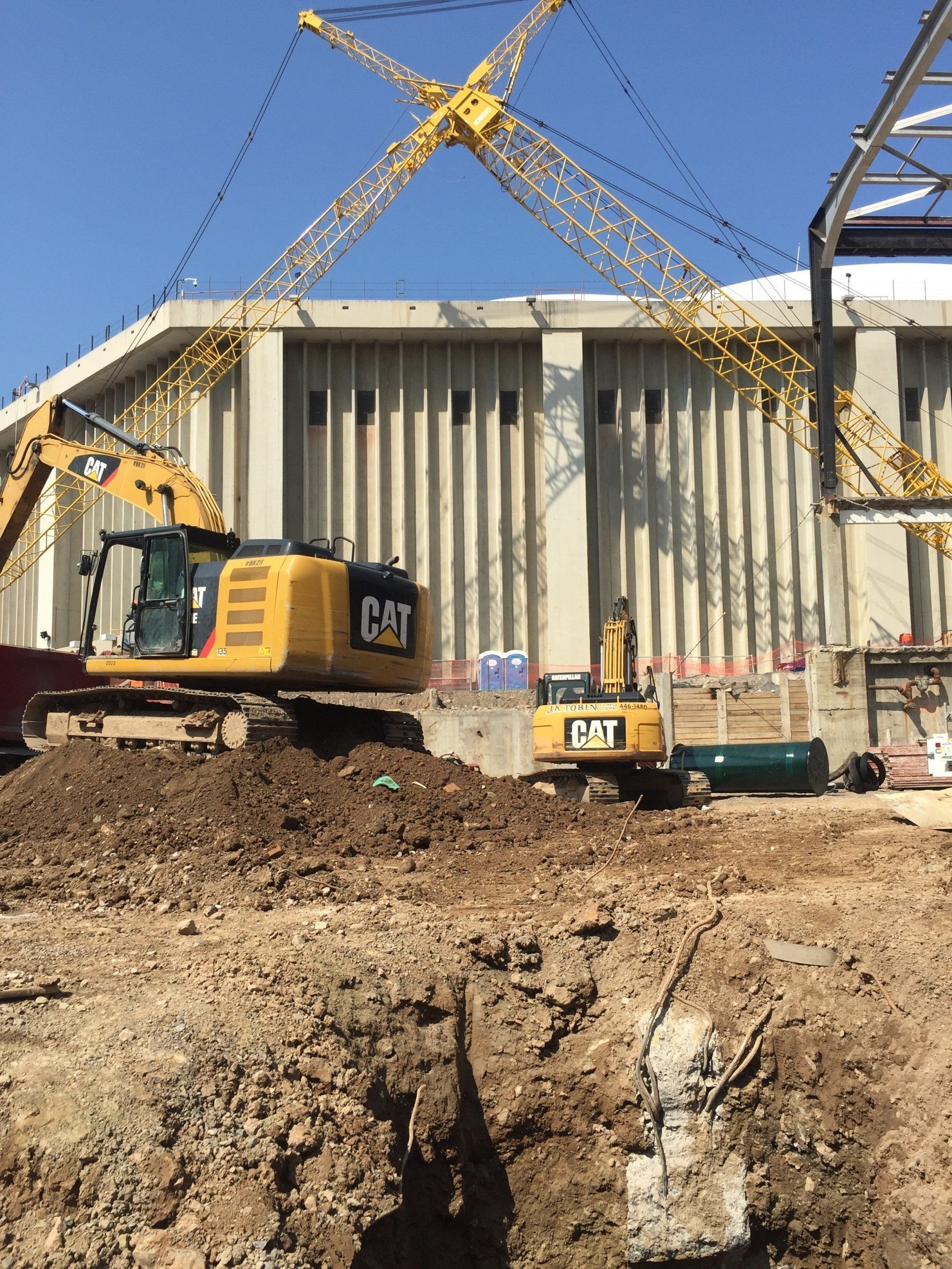 a construction site with a cat excavator and a crane in the background .