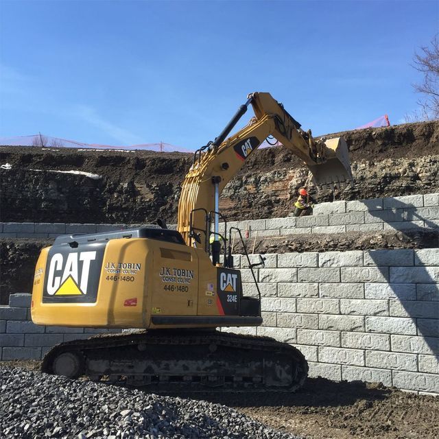 a cat excavator is parked in front of a brick wall