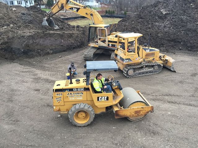 a man is driving a cat roller next to a bulldozer