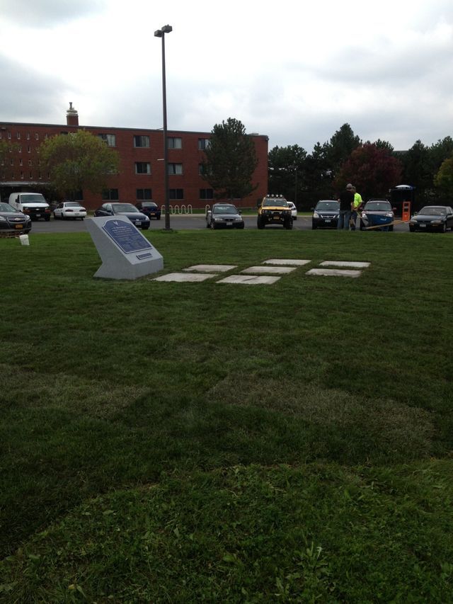 several cars are parked in a grassy area in front of a brick building