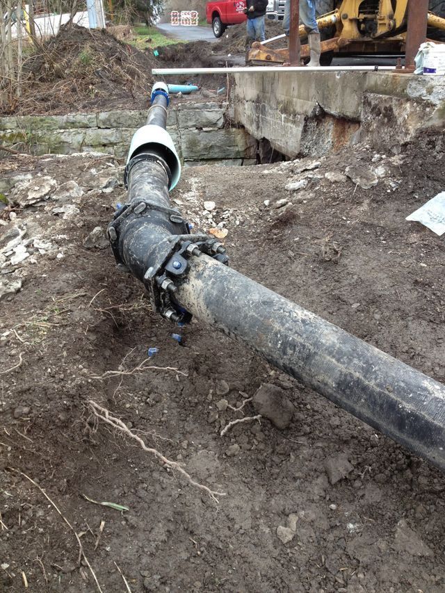 a black pipe is laying in the dirt on the ground .