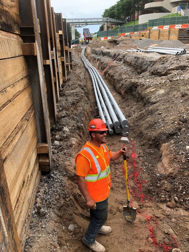 a construction worker is standing in the dirt holding a shovel .