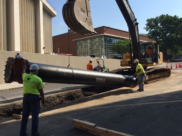 a large pipe is being lifted by a large excavator