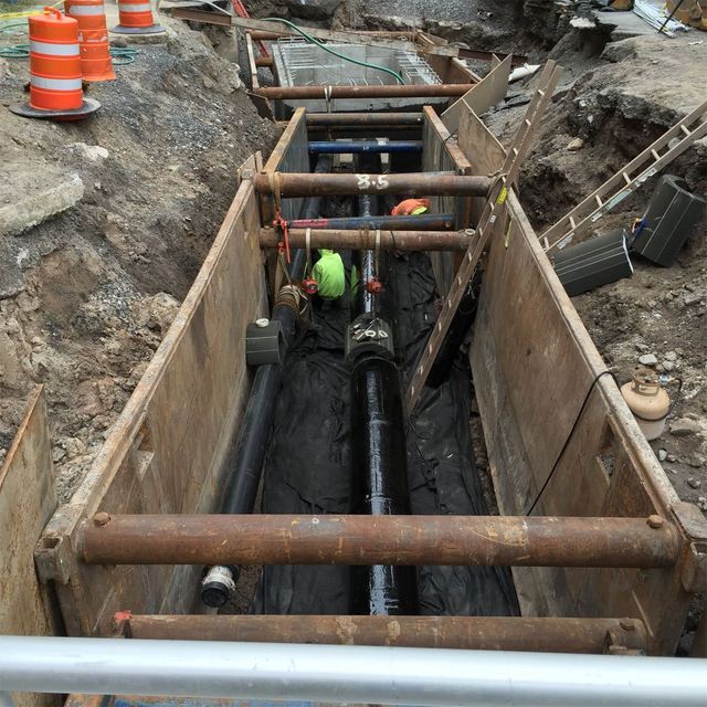 a man in a yellow vest is working on a pipe