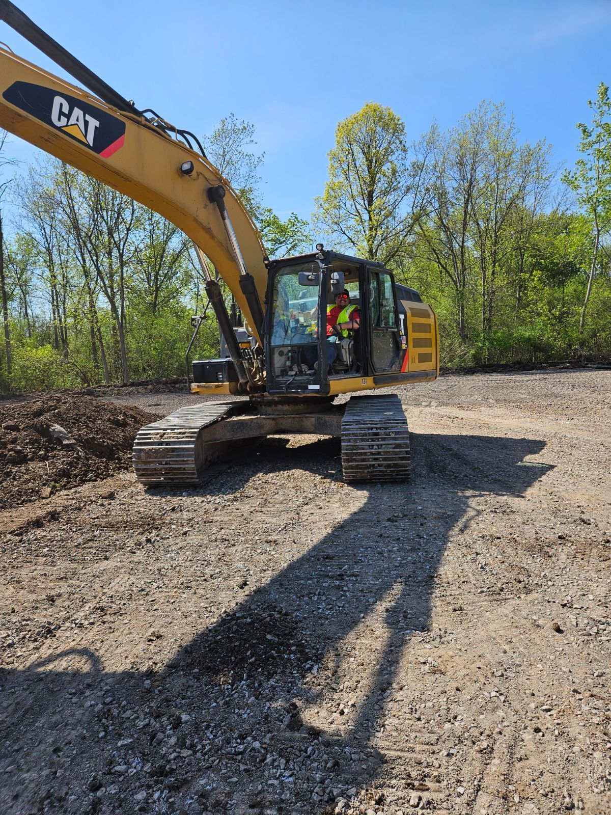 a cat excavator is sitting on top of a dirt field .