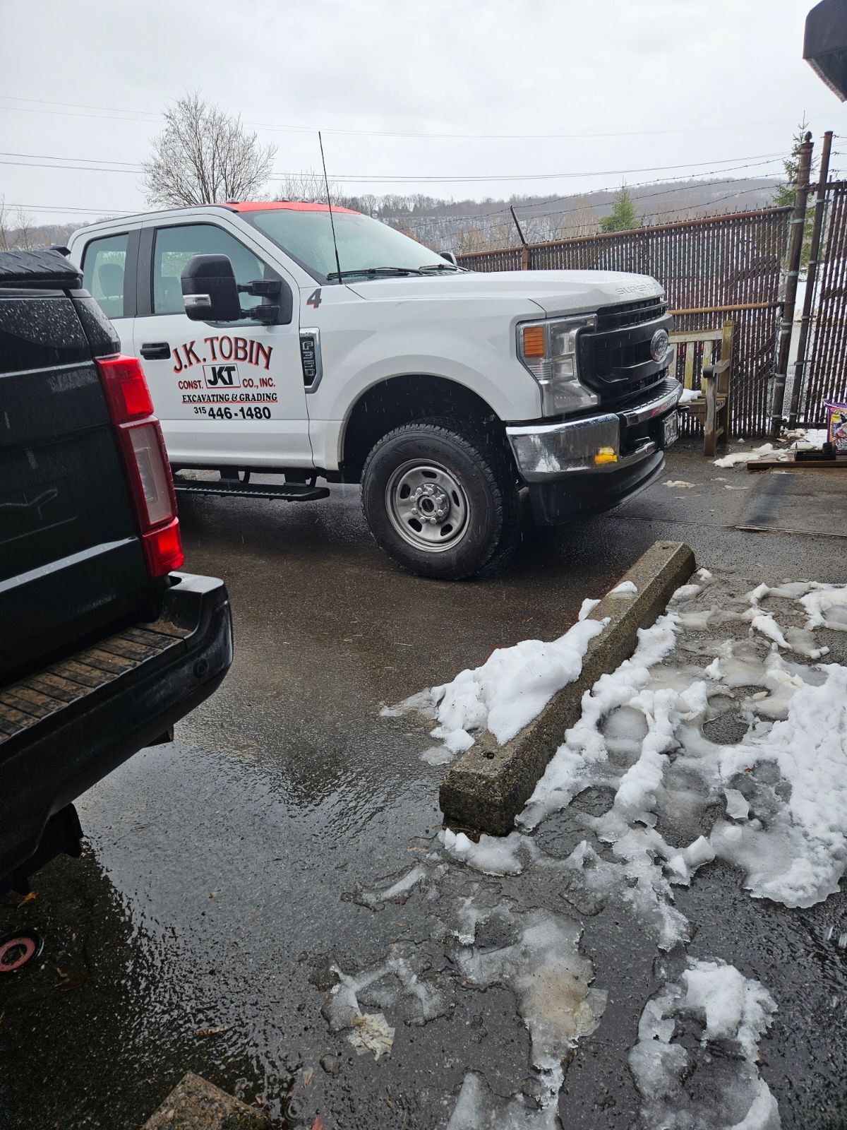 a white truck is parked next to a black truck in a parking lot .