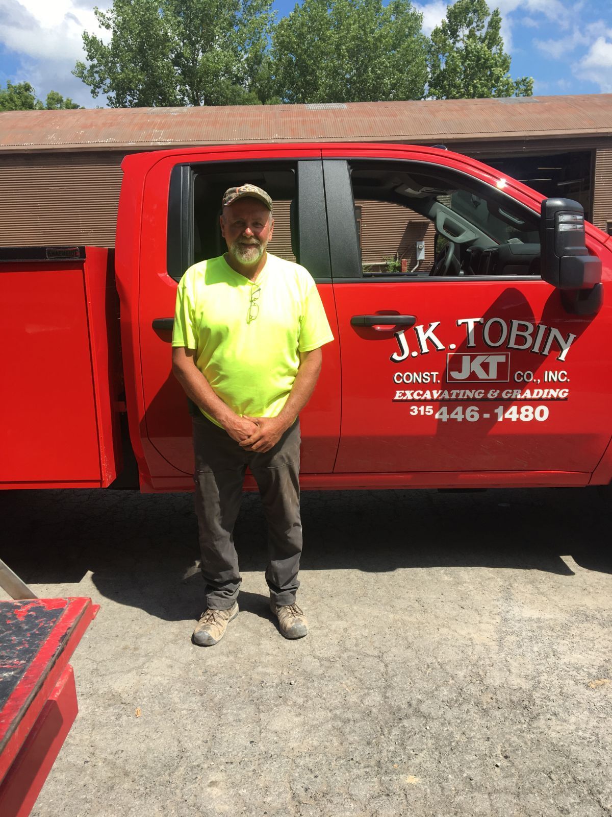 a man in a yellow shirt is standing in front of a red truck .