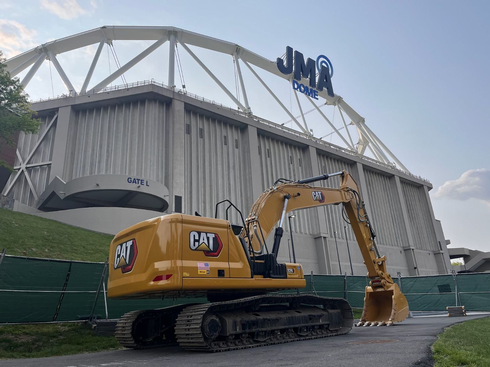 a cat excavator is parked in front of a large building .