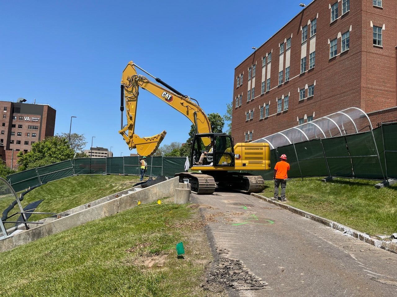 a construction site with a large yellow excavator in front of a brick building