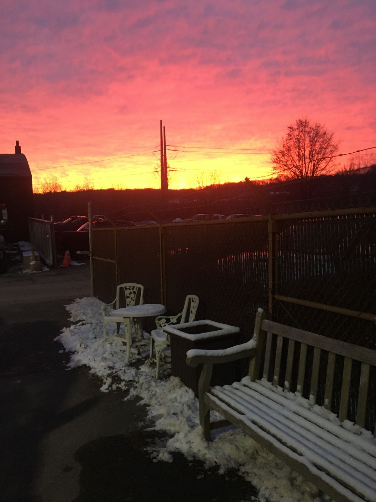 a sunset with a bench and chairs in the foreground