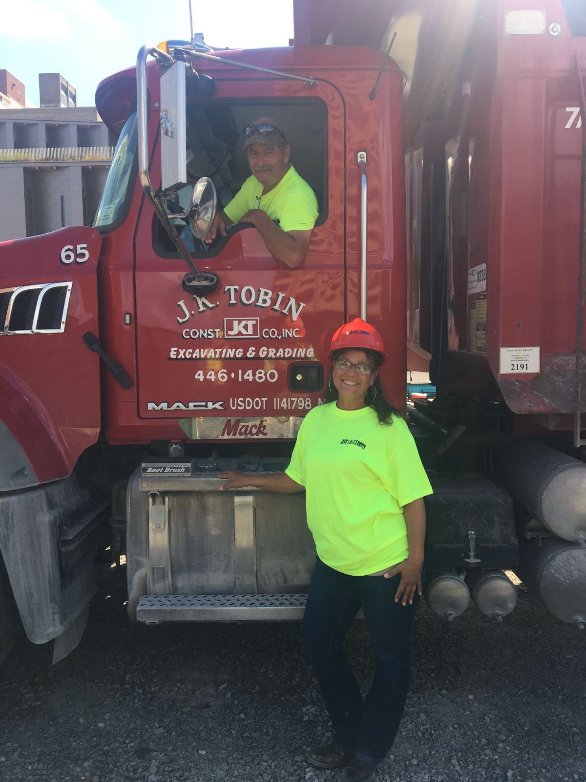 a woman is standing in front of a red dump truck