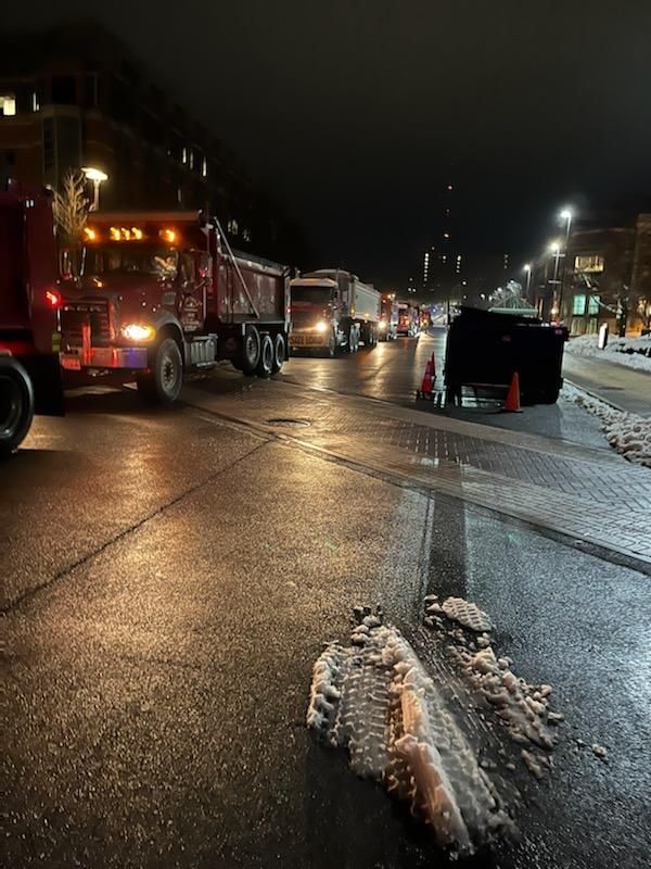 a row of trucks are parked on the side of the road at night .