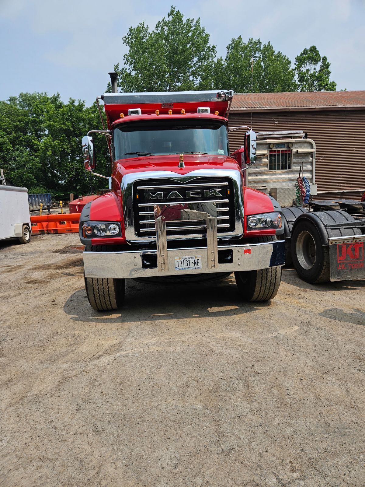 a red mack dump truck is parked in a dirt lot
