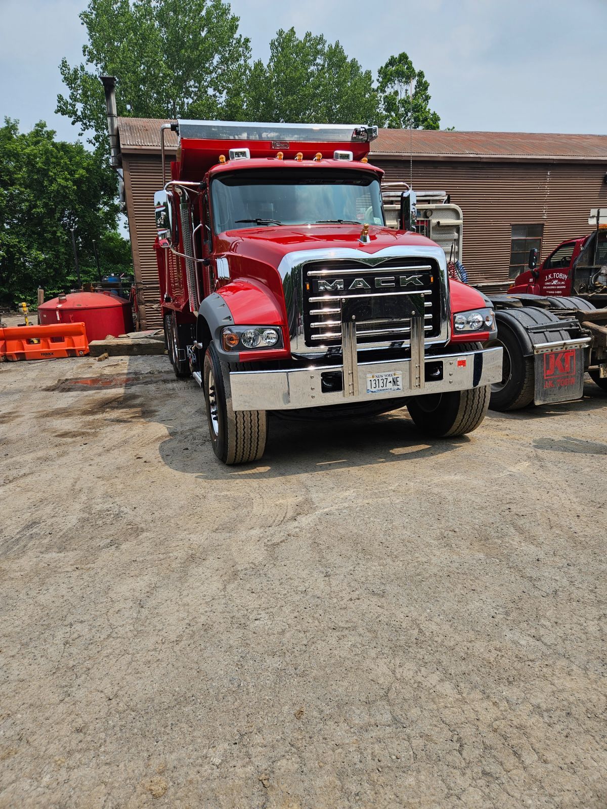 a red mack dump truck is parked in a dirt lot