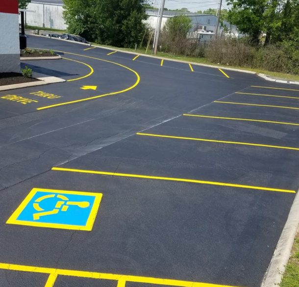 A parking lot with yellow-painted spaces, including a blue and yellow accessibility symbol.