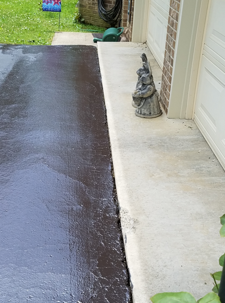 A paved area bordering a concrete garage entrance with a small decorative statue placed on the step.
