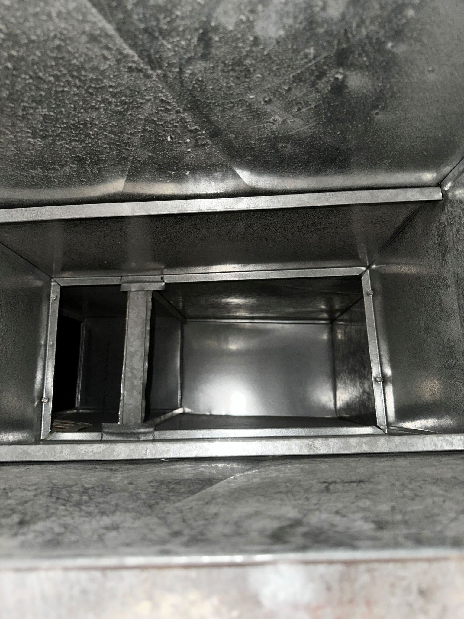 A black and white photo of a metal duct.