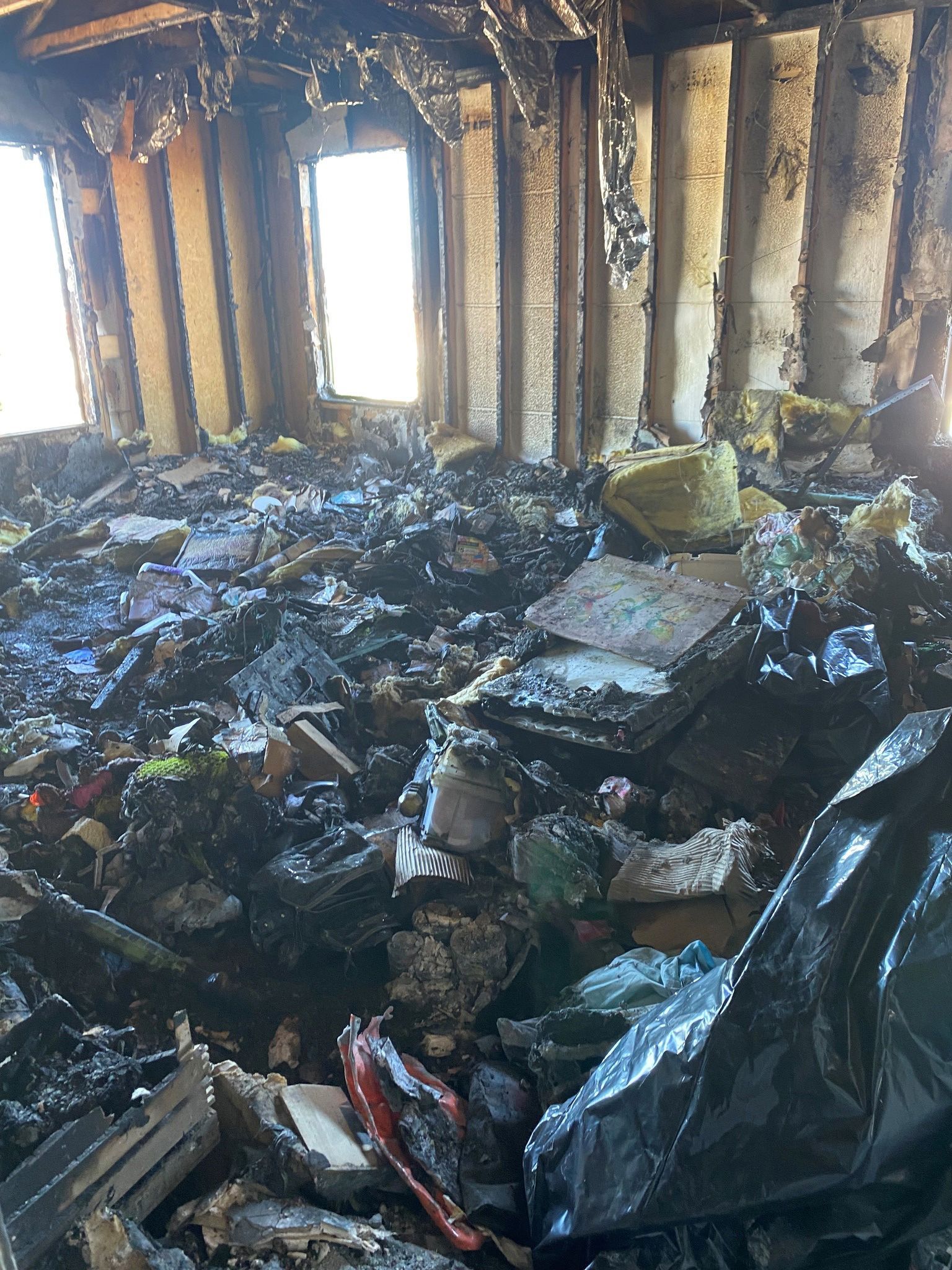 A room with a lot of trash in it and a black tarp on the floor.