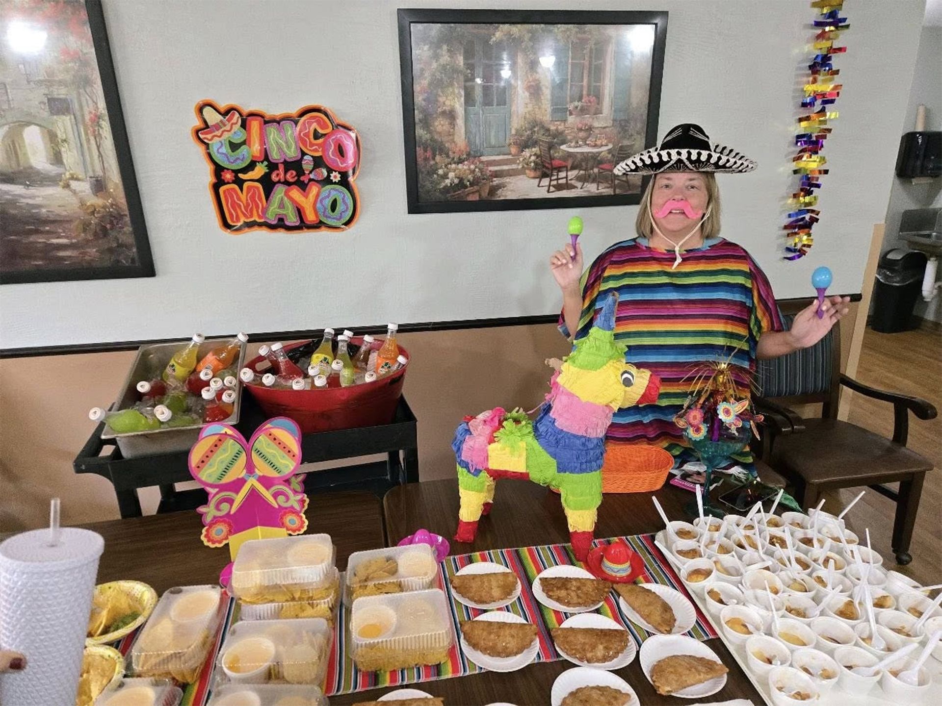 Woman in sombrero and poncho celebrates Cinco de Mayo, with food and decorations.