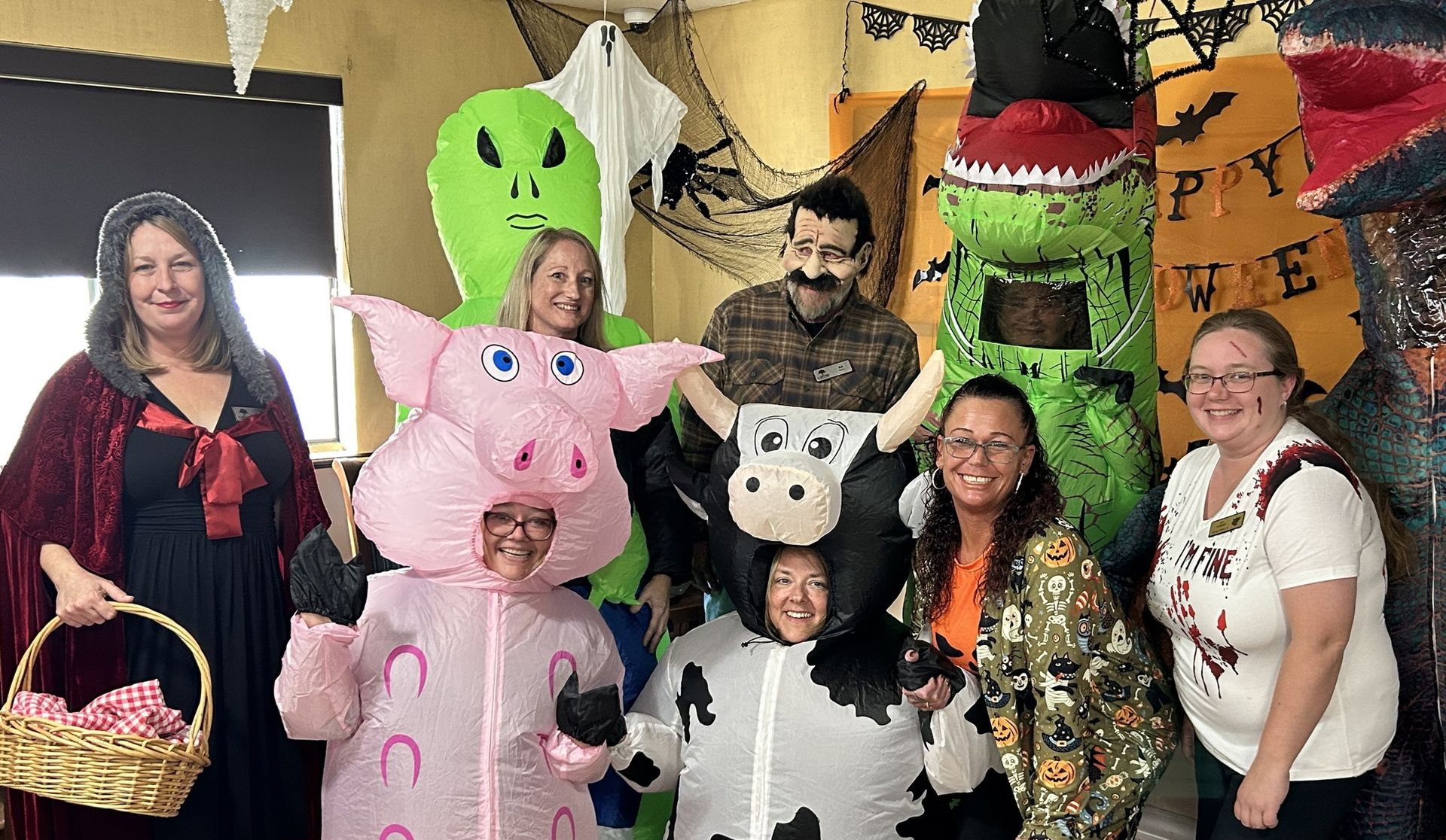 Group of people in Halloween costumes posing in front of decorations.