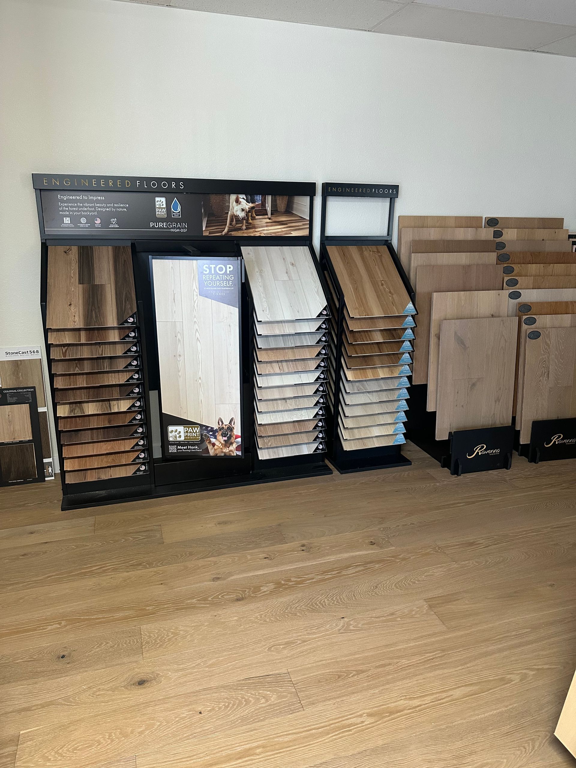 Display of wood flooring samples in a showroom, showcasing various colors and textures on a light-colored wood floor.