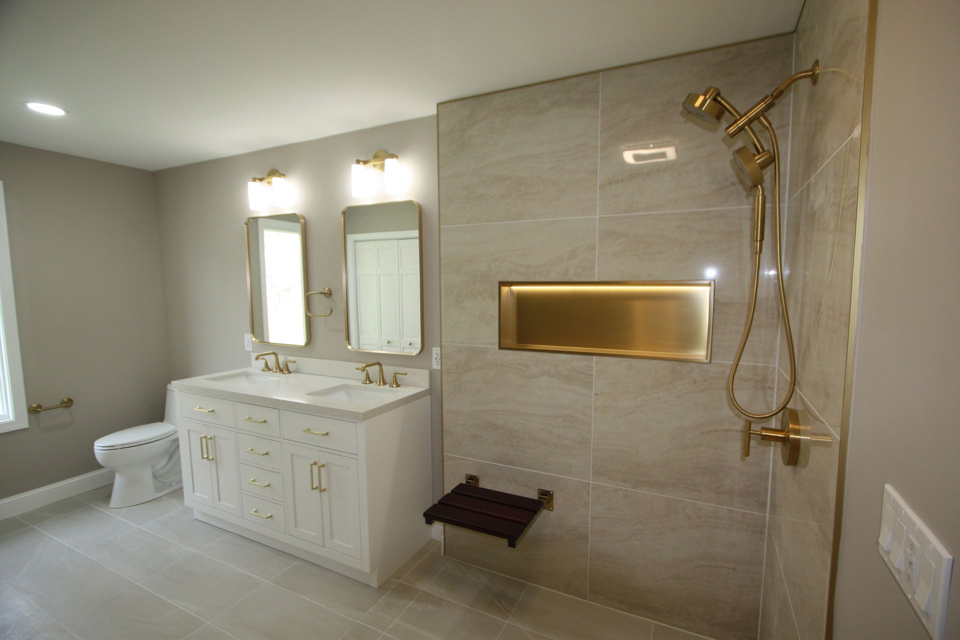 Modern accessible bathroom with double vanity, mirrors, walk-in shower, and beige tile walls