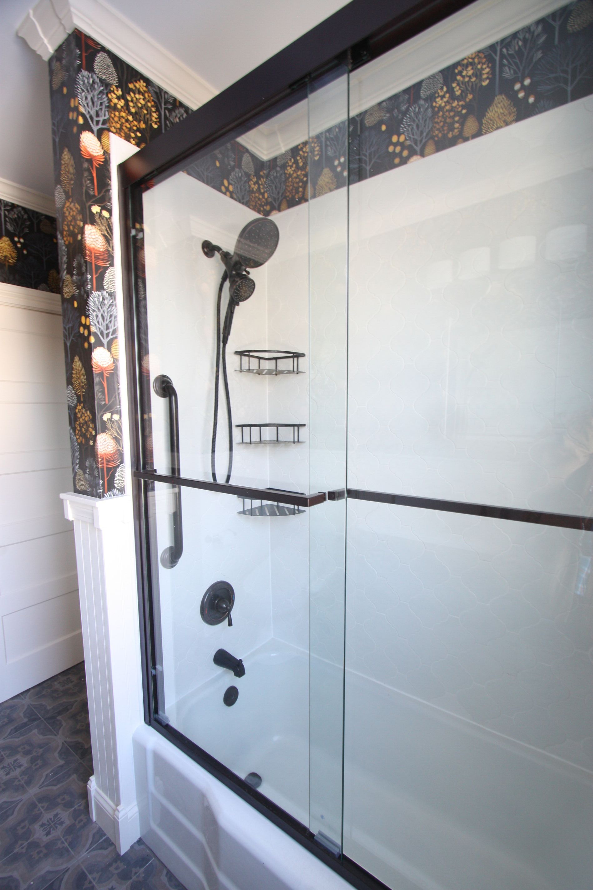 Modern bathroom shower with glass enclosure, chrome fixtures, and dark decorative tile trim