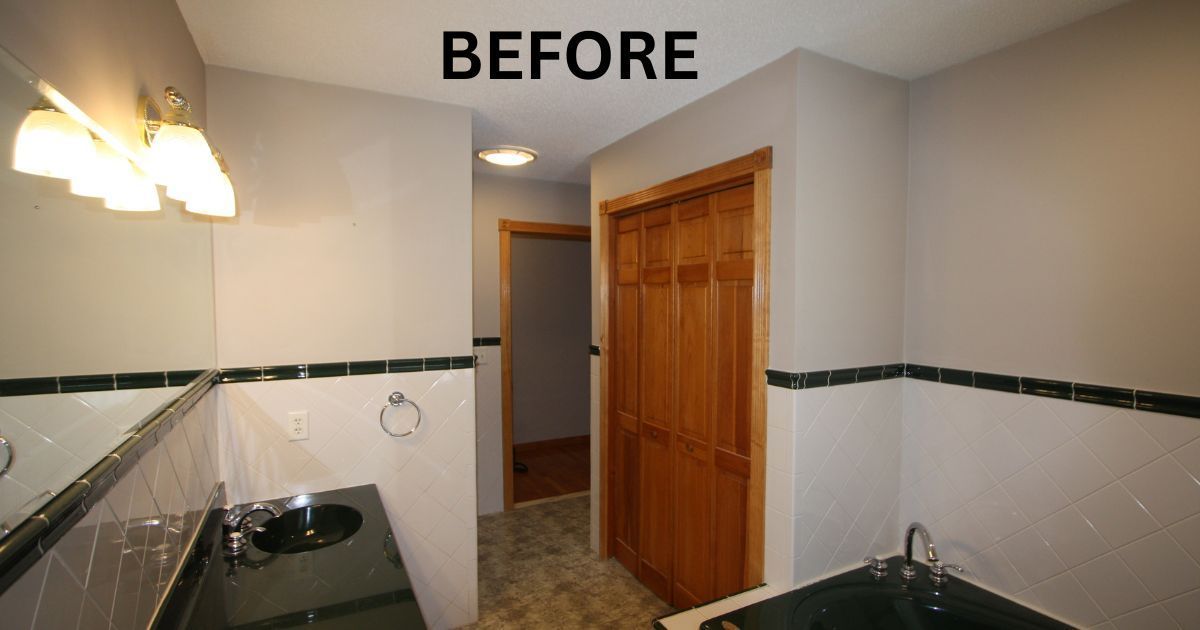 Before view of a bathroom with white tile walls, dark trim, a sink, mirror, and wooden door.