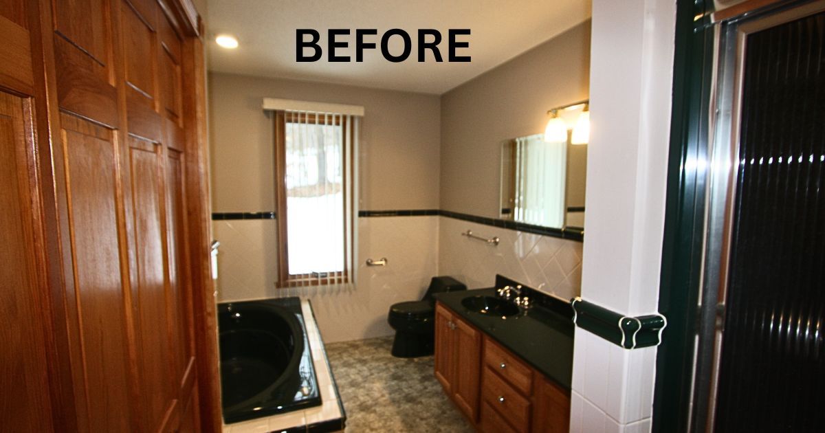 Before photo of a small bathroom with wood vanity, black tub, and window in the back.