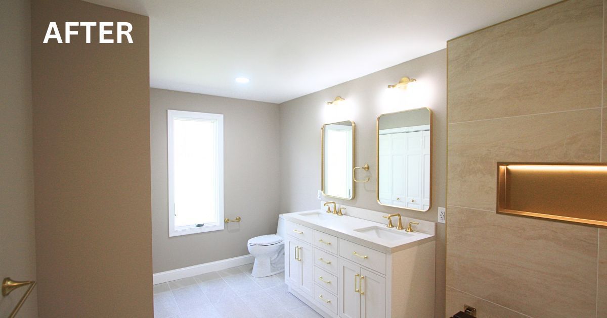 Bright renovated bathroom with white vanity, gold mirrors, and beige tile walls.