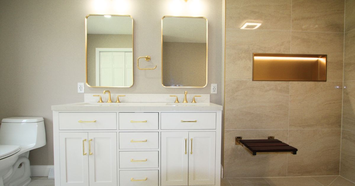 Modern bathroom with double vanity, mirrors, toilet, and tiled wall with recessed shelf and bench.