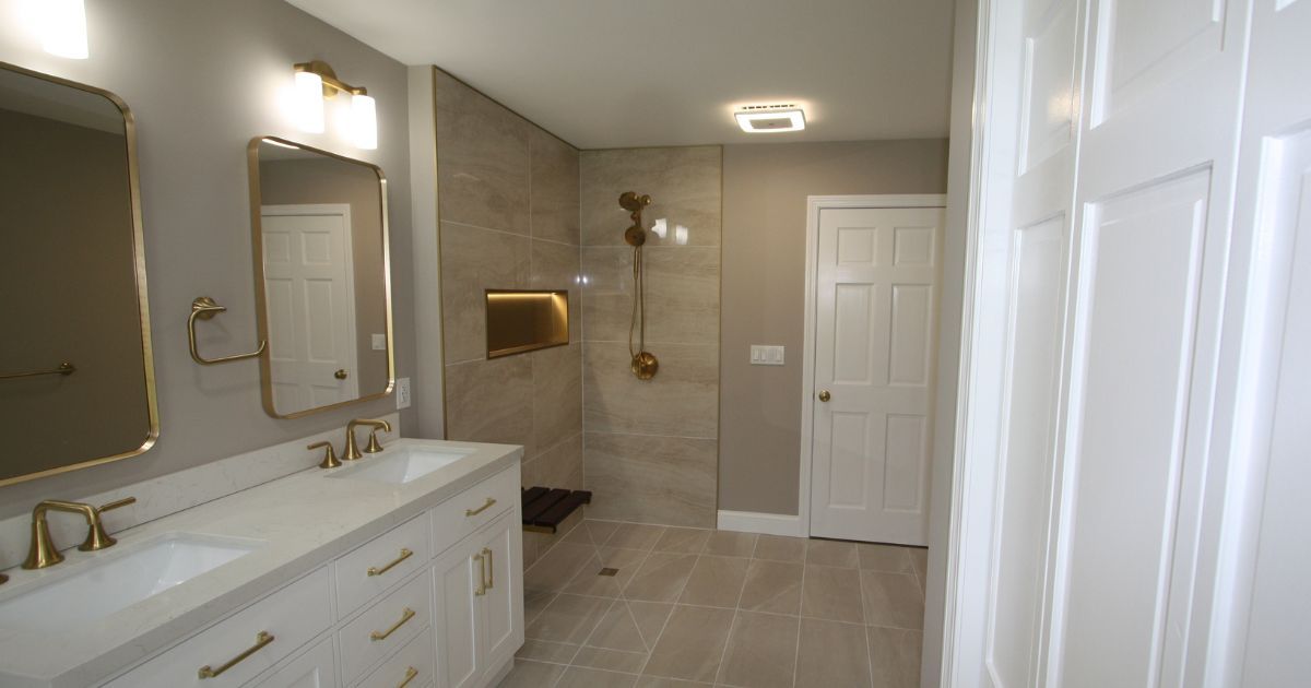 Spacious modern bathroom with double vanity, large mirrors, walk-in shower, and white cabinetry.